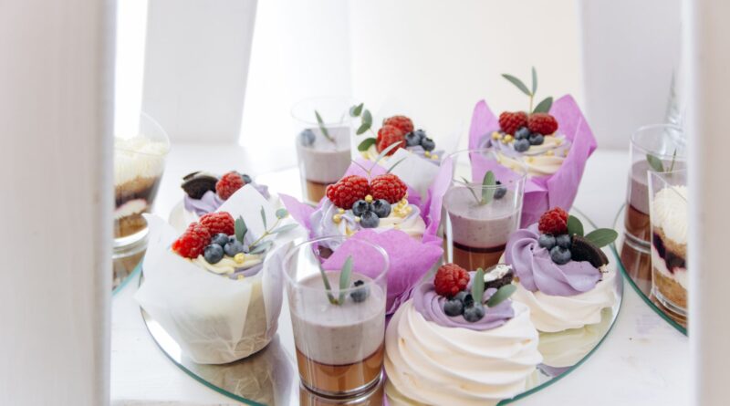A delectable assortment of cupcakes and desserts topped with fresh raspberries and blueberries, perfect for food photography.