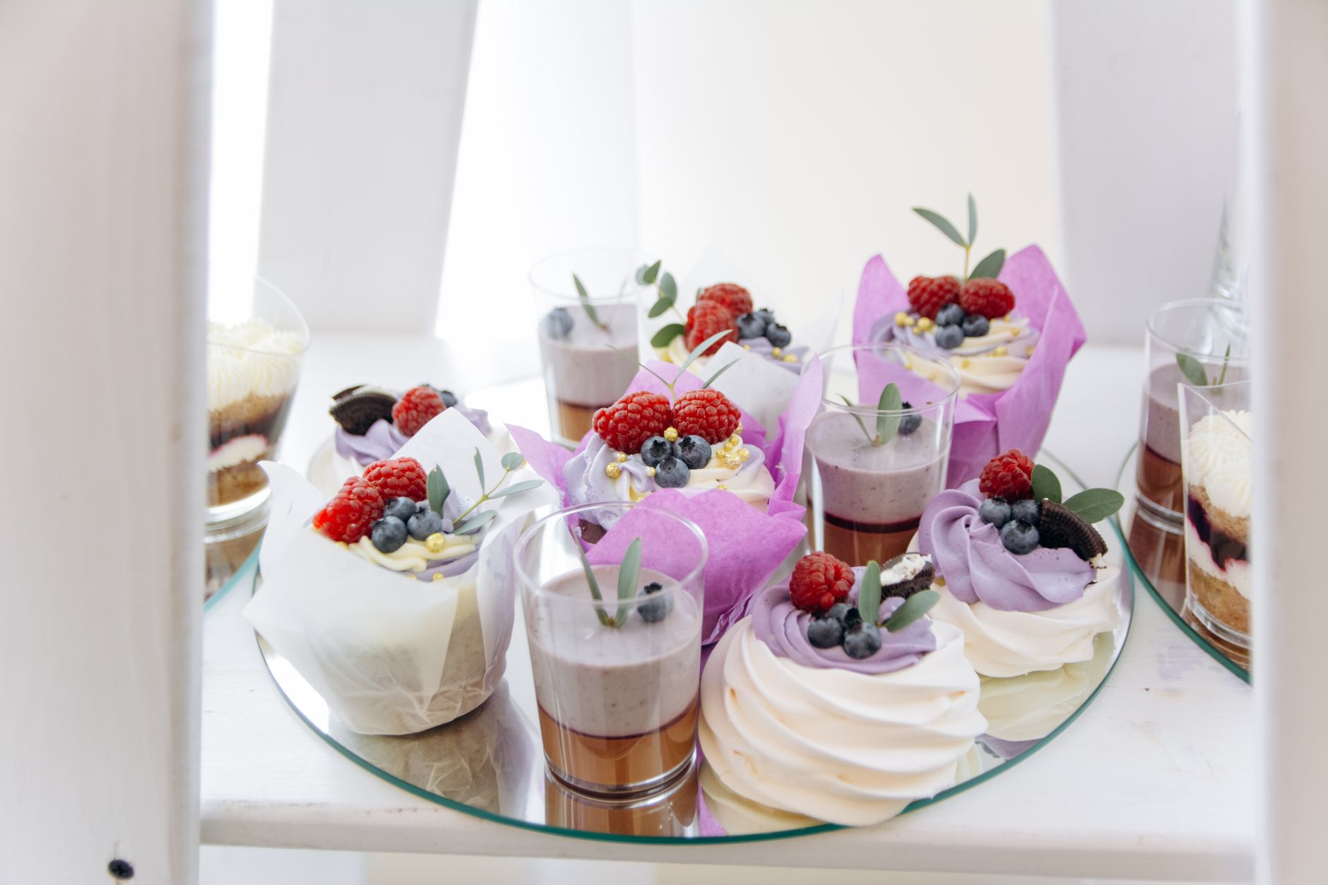 A delectable assortment of cupcakes and desserts topped with fresh raspberries and blueberries, perfect for food photography.