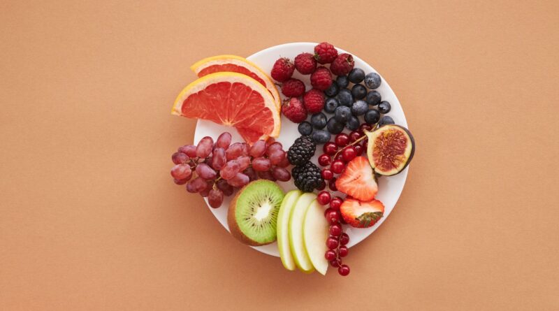 Colorful assortment of fresh fruits on a plate, perfect for healthy eating and vegan diet ideas.