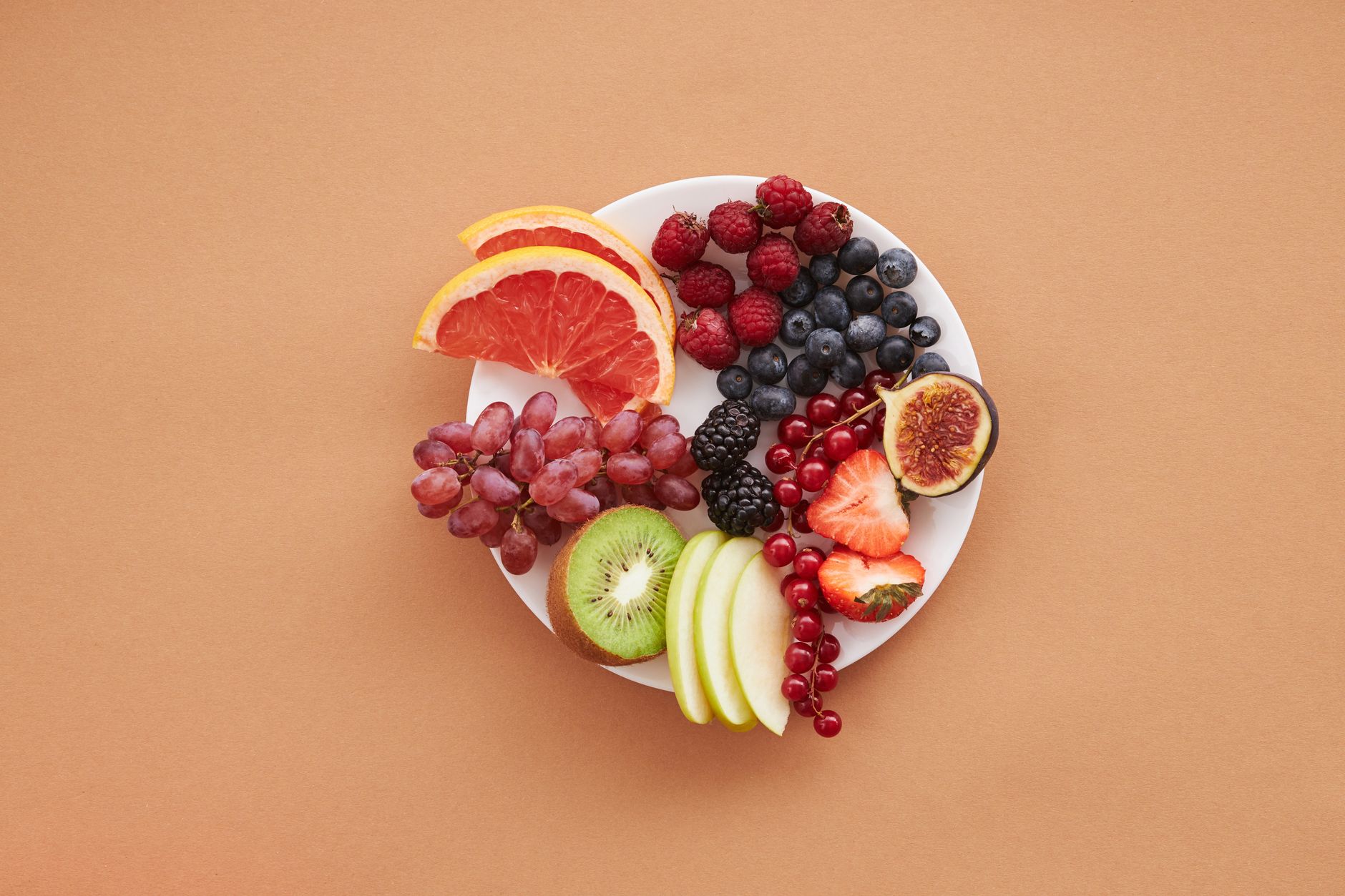 Colorful assortment of fresh fruits on a plate, perfect for healthy eating and vegan diet ideas.