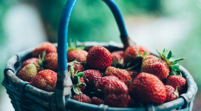 Vivid close-up of fresh, juicy strawberries overflowing in a wicker basket.