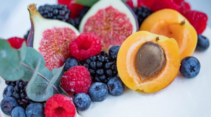 Vibrant assortment of fresh fruits including figs, apricots, berries, and leaves.