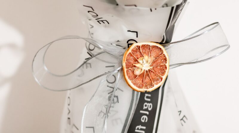 A close-up of a bouquet wrapped with a dried orange slice and ribbon, creating an elegant floral presentation.