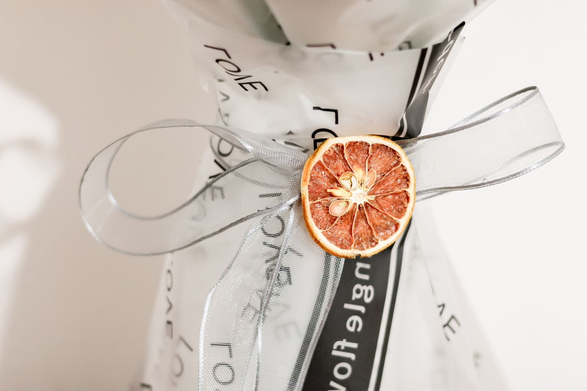 A close-up of a bouquet wrapped with a dried orange slice and ribbon, creating an elegant floral presentation.