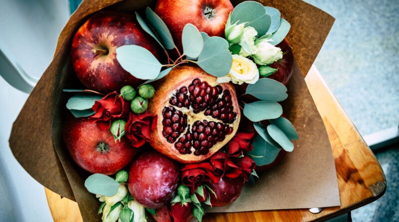 Букеты из конфет и ягод: сладкие подарки, которые запомнятся A vibrant autumn bouquet featuring apples, pomegranate, and flowers wrapped in paper.