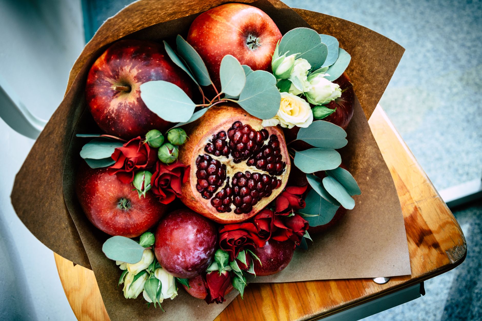 Букеты из конфет и ягод: сладкие подарки, которые запомнятся A vibrant autumn bouquet featuring apples, pomegranate, and flowers wrapped in paper.