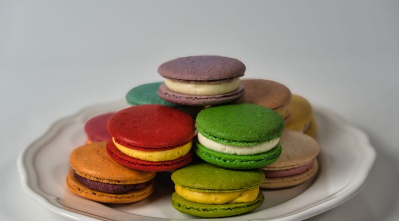 A stack of colorful French macarons on a plate, perfect for dessert enthusiasts.