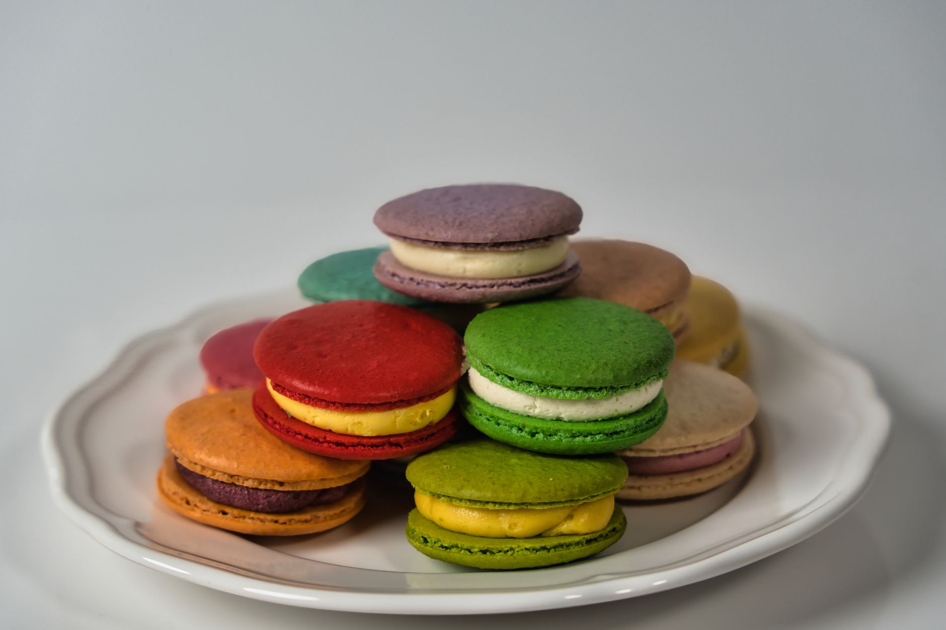 A stack of colorful French macarons on a plate, perfect for dessert enthusiasts.